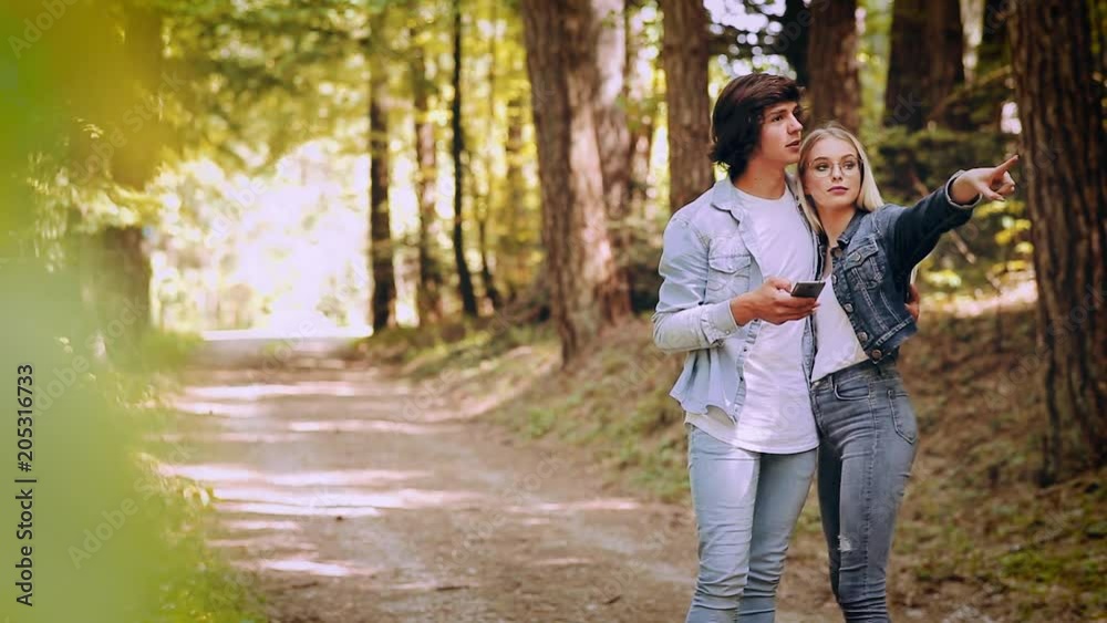 Young Couple Using Smartphone While Walks Through Forest Young Couple Using Smartphone While Walks Through Forest
