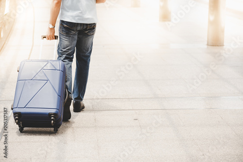 Handsome traveler guy drag suitcase to street at metropolis or city. Attractive man get lost in the big city. He loves travel by his self or alone. He get long weekend holiday. copy space, hot weather