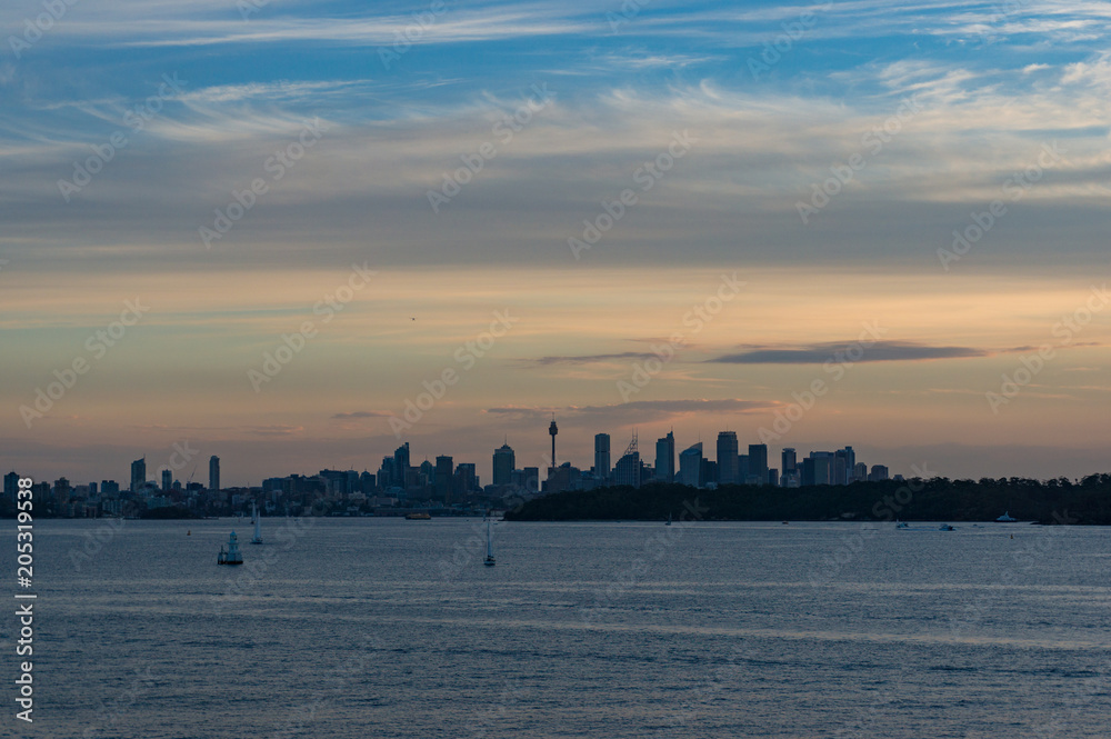 Distant silhouette of Sydney cityscape at dusk, on sunset