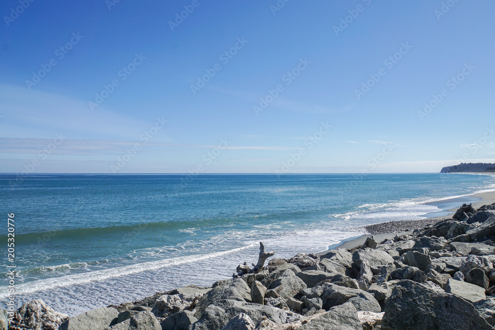 sea wave and breeze at rock shore in New Zealand with bright blue sky
