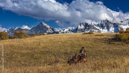 Older Cowboy leads packhorse across historic Last Dollar Ranch on Hastings Mesa, SW Colorado, San Juan Mountains