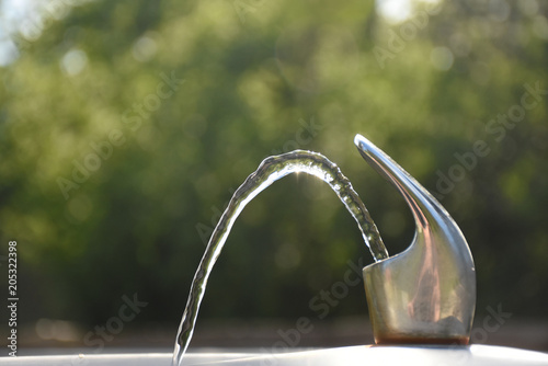 Outdoor Water Fountain with Flowing Water against Blurred Outdoors Background © annarepp