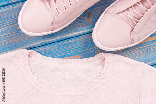 Pair of pink womanly leather shoes and sweater on old blue boards