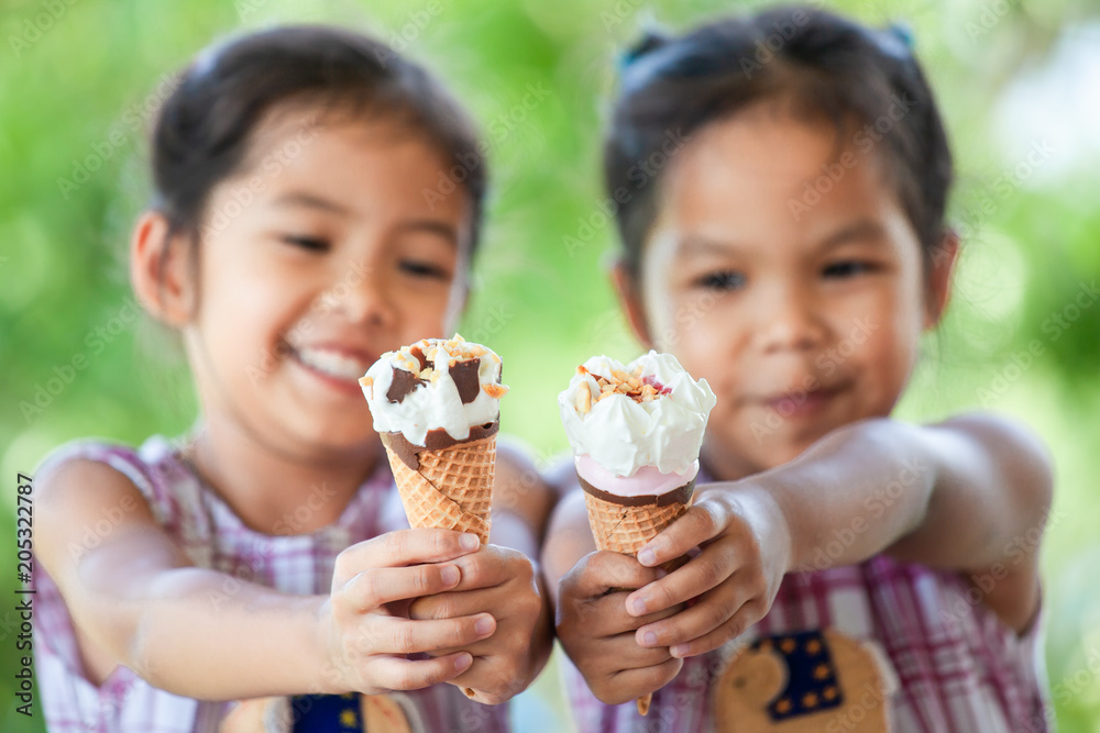 Two asian little girls  holding delicious ice cream waffle cone together in hand with fun and happiness