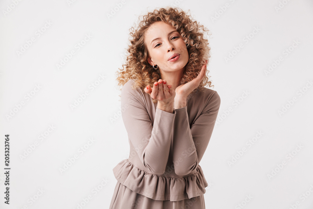 Lovely blonde curly woman in dress sends air kiss
