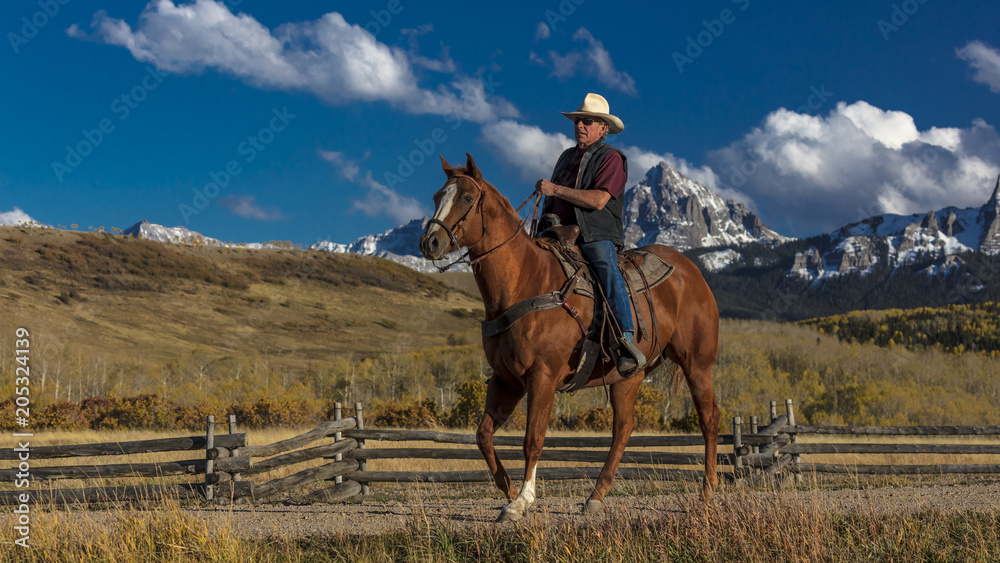 Cowboy rides horse across historic Last Dollar Ranch on Hastings Mesa, SW Colorado, San Juan Mountains Cowboy rides horse across historic Last Dollar Ranch on Hastings Mesa, SW Colorado, San Juan Mountains