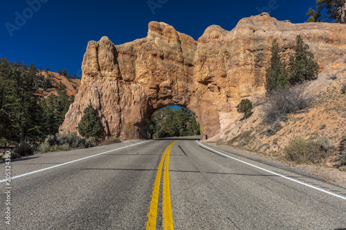 Yellow line divides Utah state highway and drives through Red Rock with hole in center
