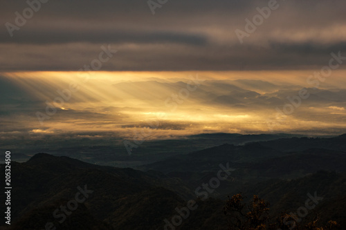 Golden sunrise heavenly sky ray light at mountain hill valley landscape with cloudy background