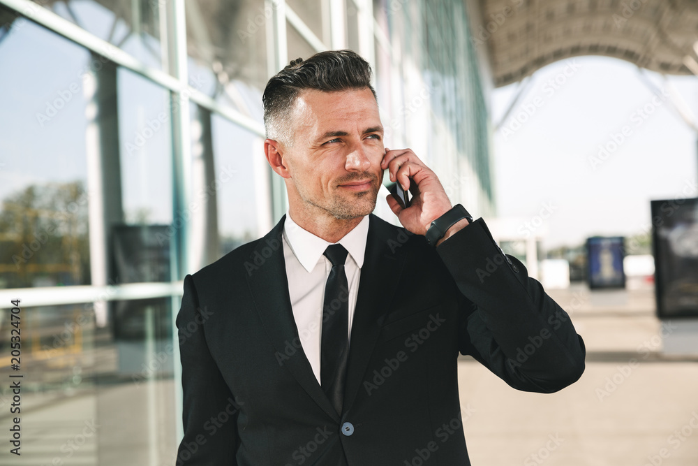 Smiling businessman dressed in suit walking outside Smiling businessman dressed in suit walking outside