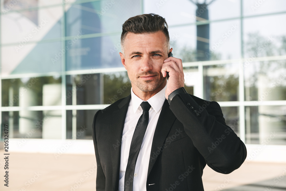 Smiling businessman dressed in suit walking outside Smiling businessman dressed in suit walking outside