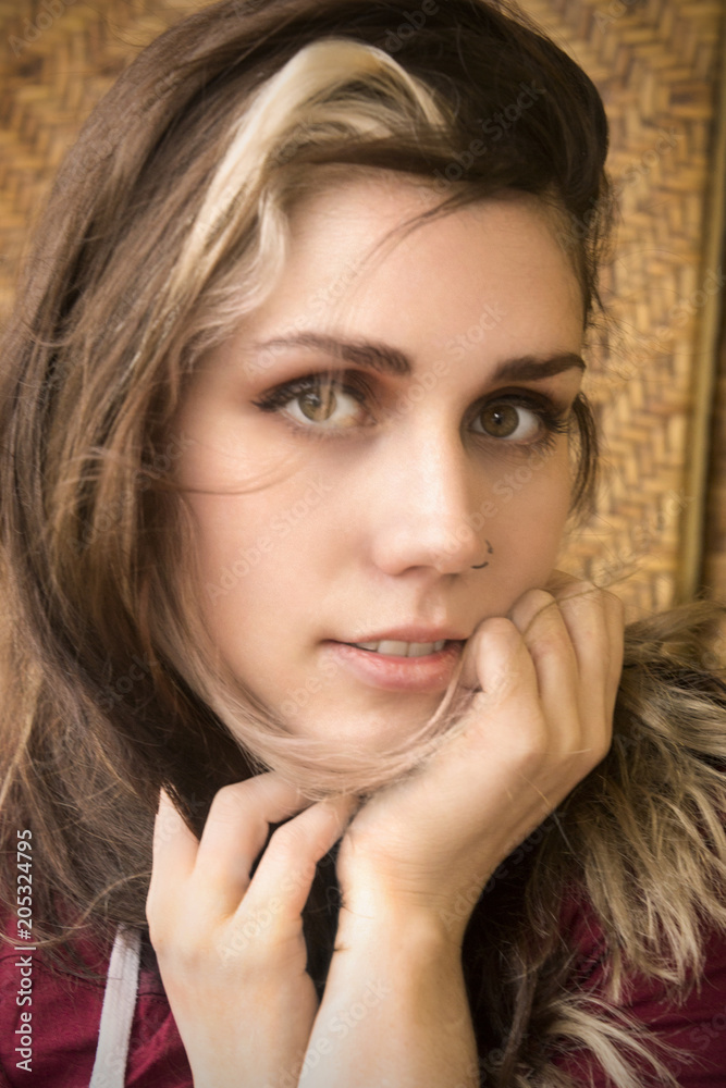 Head and shoulders portrait of young woman in window light.