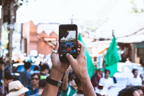 Young man taking photo of events using mobile phone