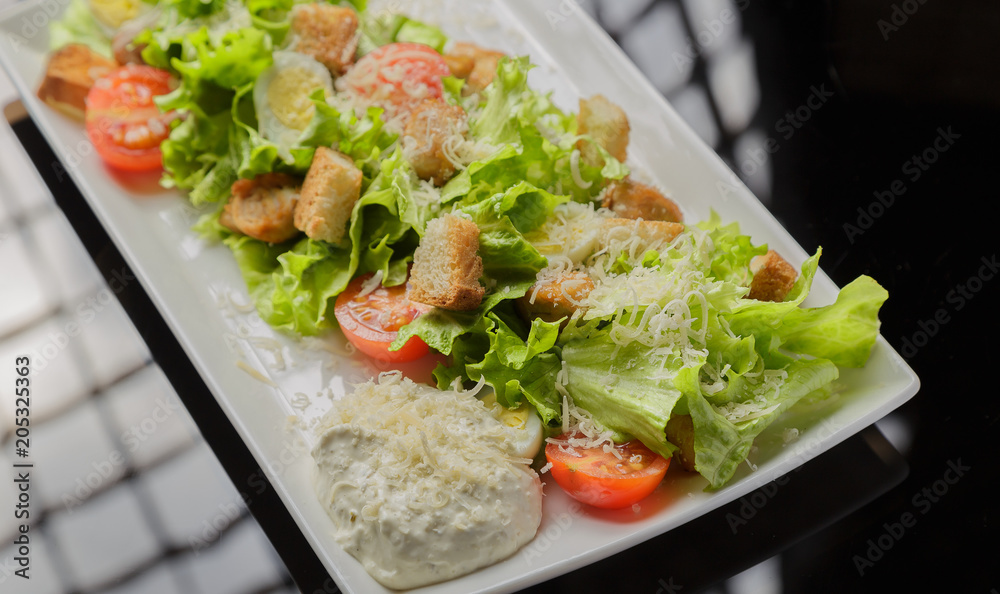 Caesar salad on a white plate and a glass background Caesar salad on a white plate and a glass background
