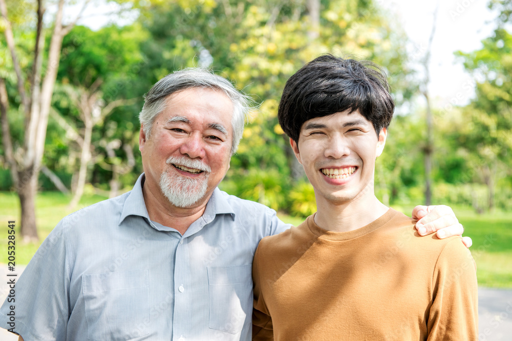 Father and son in park portrait. Retired chinese father with his son holding each other, happy and smiling. Successful family love and relationship concept. Father and son in park portrait. Retired chinese father with his son holding each other, happy and smiling. Successful family love and relationship concept.