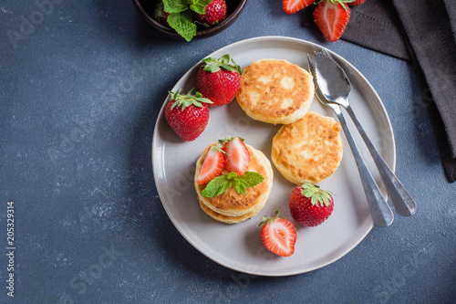 Cottage cheese pancakes with strawberry on blue concrete table background. Breakfast or Lunch Concept. Top view, copy space