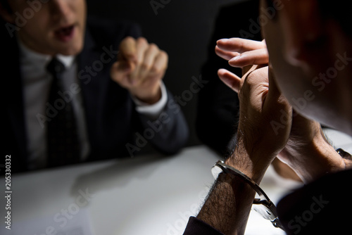 Criminal man with handcuffs being interviewed in interrogation room after committed a crime photo