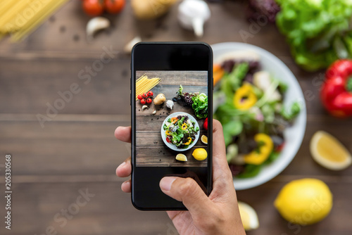 Food blogger using smartphone taking photo of beautiful salad