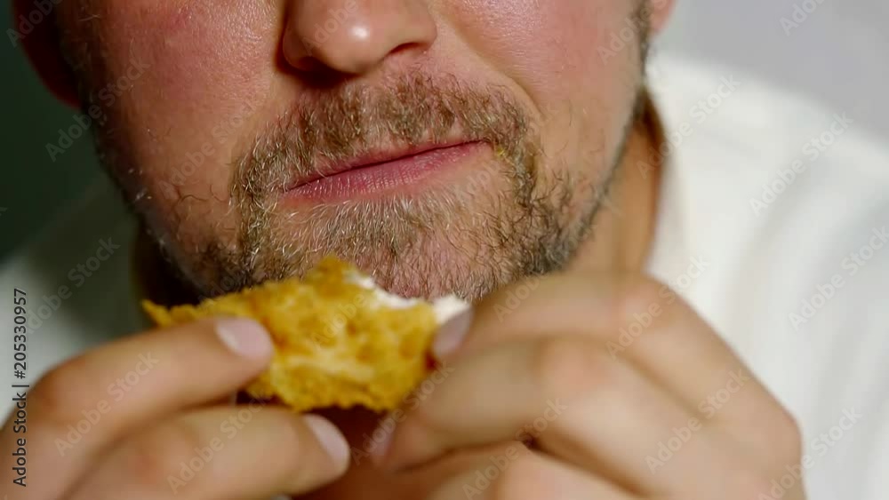 close up shot of a bearded man who bites a piece of chicken and eats a meal close up shot of a bearded man who bites a piece of chicken and eats a meal