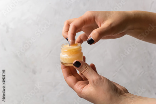 female hands holding cosmetic product in a glass jar