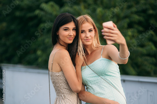 Brunette and blonde are photographed and enjoy life. Sunny day. Summer