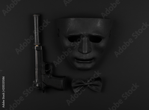 pistol with a silencer and a black mask on a black isolated background