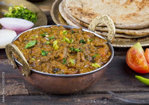 Indian Cuisine Sev Tamatar Also Called Sev Tamaeta or Sev Tameta is Served With Chapati, Papad, Onion or Raita. It is Made With Tomato And Onion Gravy With a Twist of Spicy Sev on Wooden Table photo