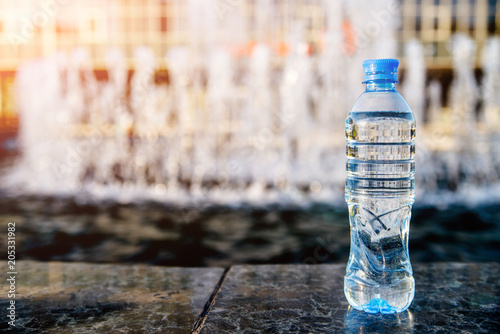 A bottle of drinking water stands on the background of the fountain 