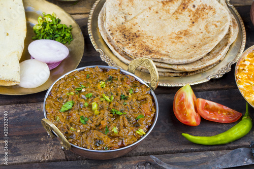 Indian Cuisine Sev Tamatar Also Called Sev Tamaeta or Sev Tameta is Served With Chapati, Papad, Onion or Raita. It is Made With Tomato And Onion Gravy With a Twist of Spicy Sev on Wooden Table photo