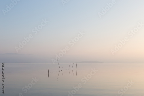 A very minimalistic view of a lake at dawn  with soft light  war