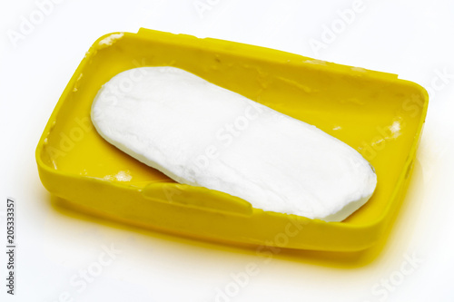 Soap residue in a yellow plastic soap dish on a white background.