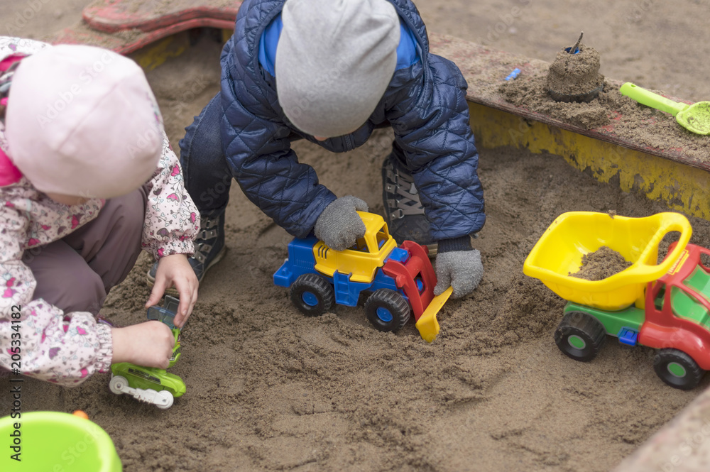 Children in warm winter clothes play in the sandbox close-up Children in warm winter clothes play in the sandbox close-up