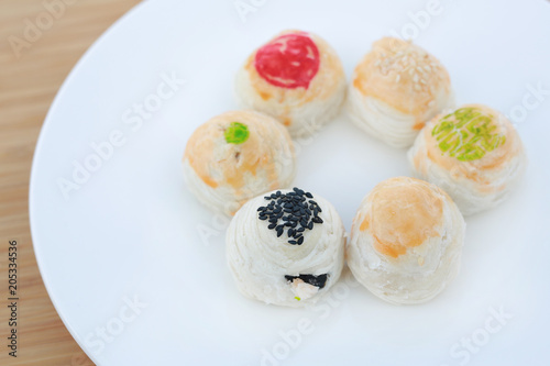 Spring roll pastry with nuts and salted eggs, chinese pastry on white plate against wooden background.