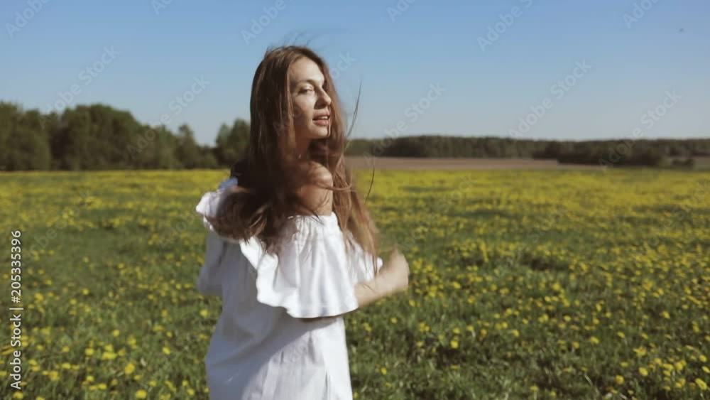 Attractive Young Woman Walks through the meadow and looks at Camera. Outdoor lifestyle portrait. Slow motion video shooting by handheld gimbal Attractive Young Woman Walks through the meadow and looks at Camera. Outdoor lifestyle portrait. Slow motion video shooting by handheld gimbal
