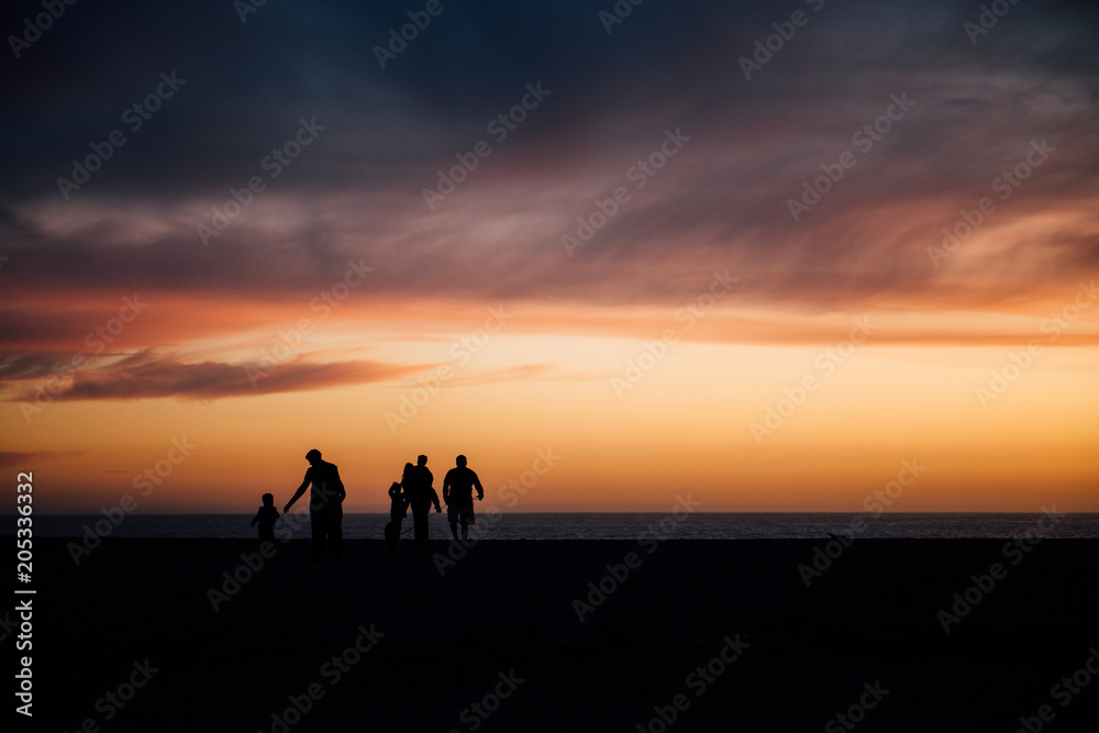 Silhouette of people walking on beach at sunset Silhouette of people walking on beach at sunset