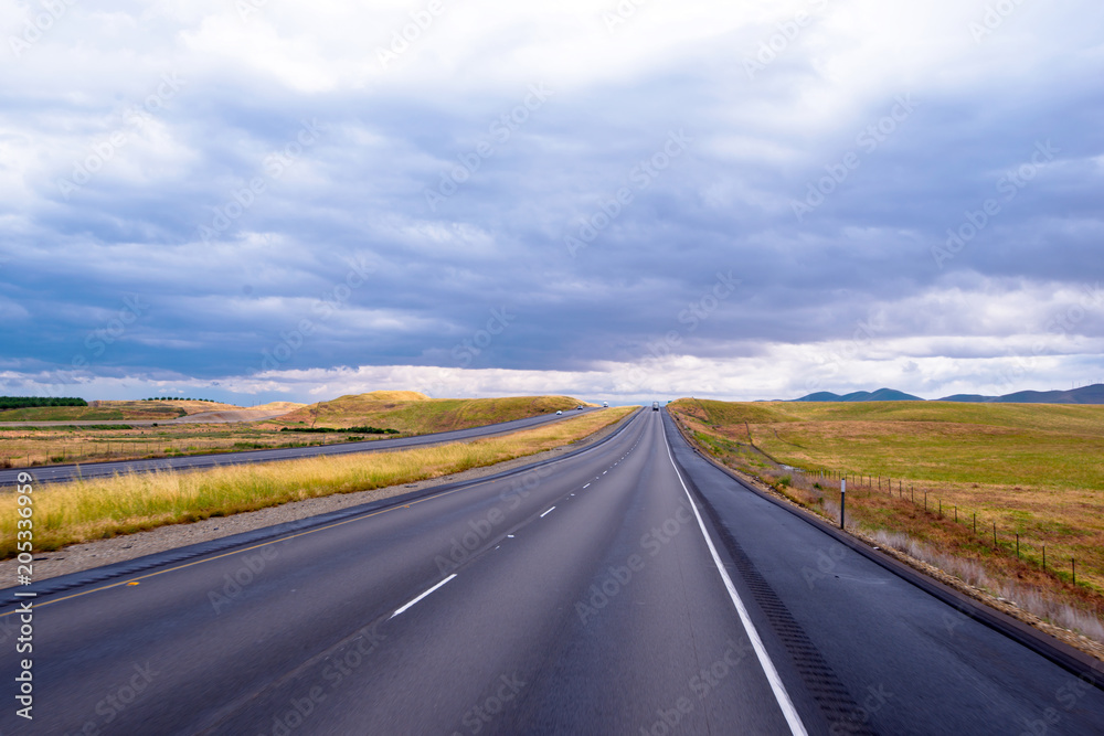 Infinite smooth road leaving the horizon in the middle of the meadows of California