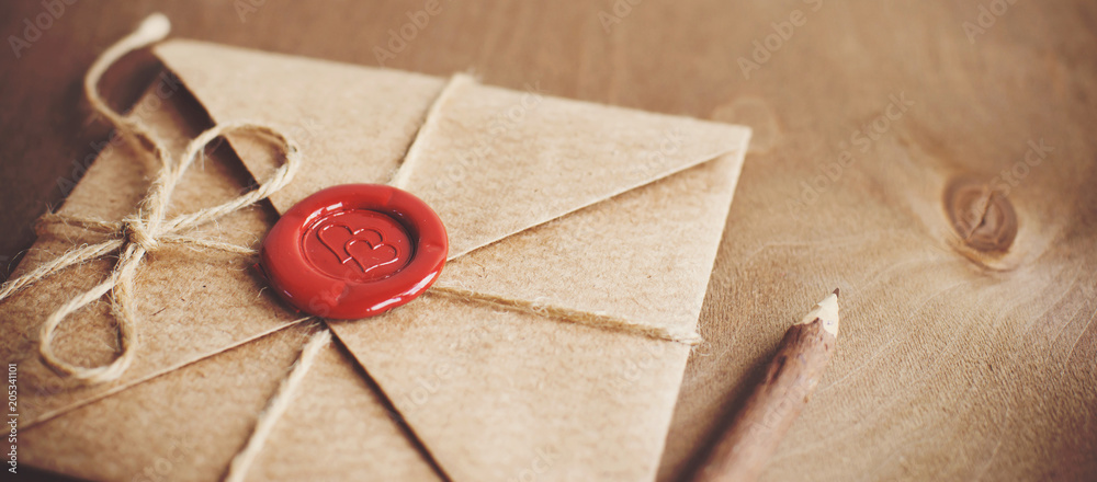 Fototapeta list miłosny w kopercie rzemiosła z pieczęcią lakowa w formie serca na tle drewnianych. Wolna przestrzeń