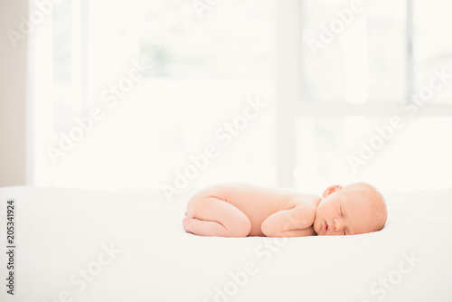 newborn baby sleeping on white bed