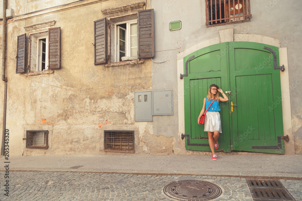 Cute attractive fashionable girl posing in the old European street. Fashion details.