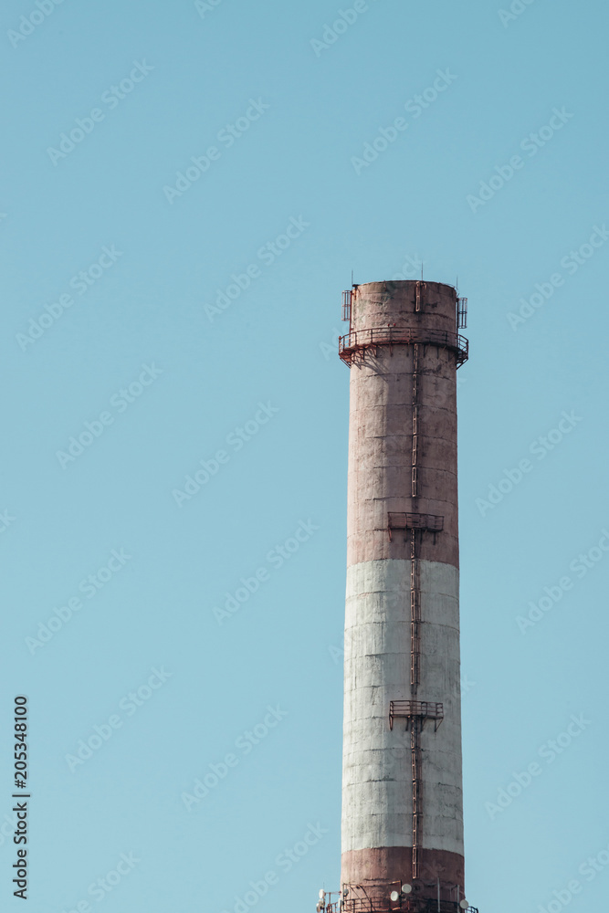 High red and white striped tube on background clear blue sky close-up. Thermal power plant with copy space. High red and white striped tube on background clear blue sky close-up. Thermal power plant with copy space.