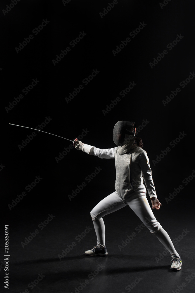 full length of female fencer in uniform posing with sword on black background full length of female fencer in uniform posing with sword on black background