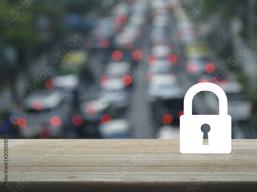 Key icon on wooden table over blur of rush hour with cars and road, Business security concept