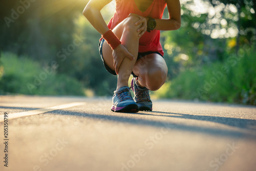 Woman runner got sports injury running on forest trail photo