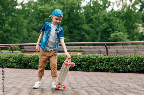 A small city boy and a skateboard. A young guy is riding in a park on a skateboard. City Style. City children. A child learns to ride a skateboard © Aliaksandr Marko