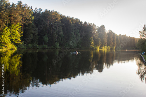 people swim by boat on a river in the forest