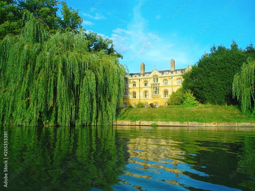 the campus of the University of Cambridge (England): an old building in a dense park, calm waters of the River Cam; summer the campus of the University of Cambridge (England): an old building in a dense park, calm waters of the River Cam; summer