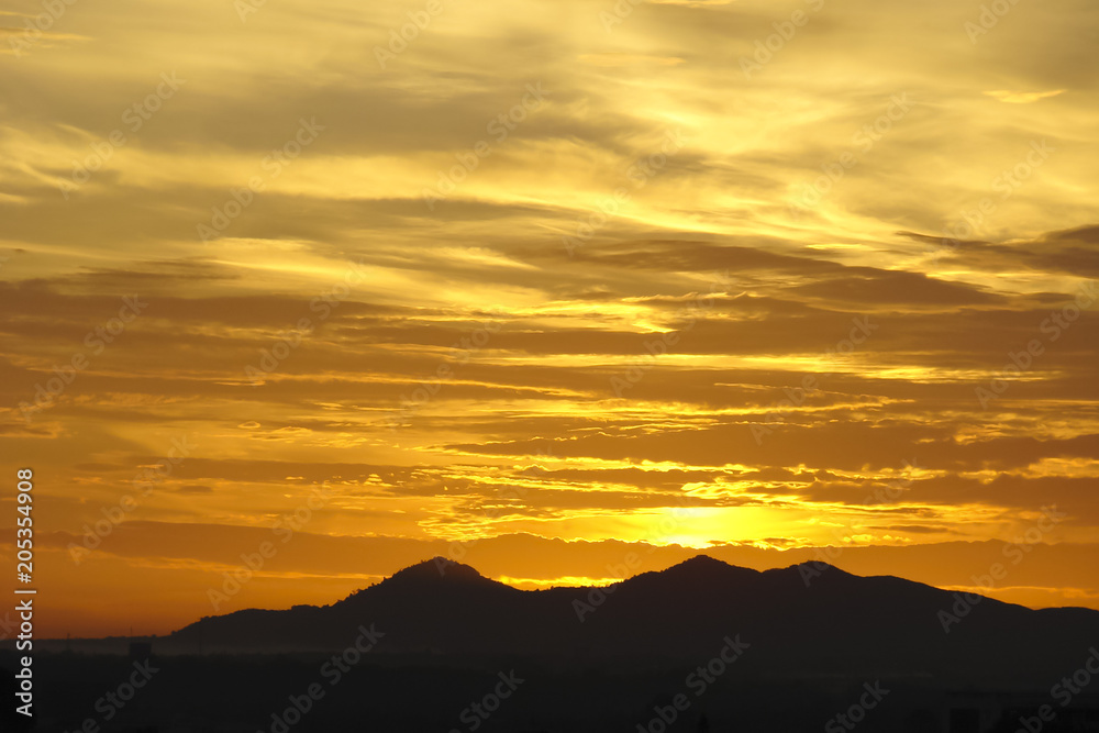 purple silhouettes of mountains against the background of a golden cloudy sky at dawn