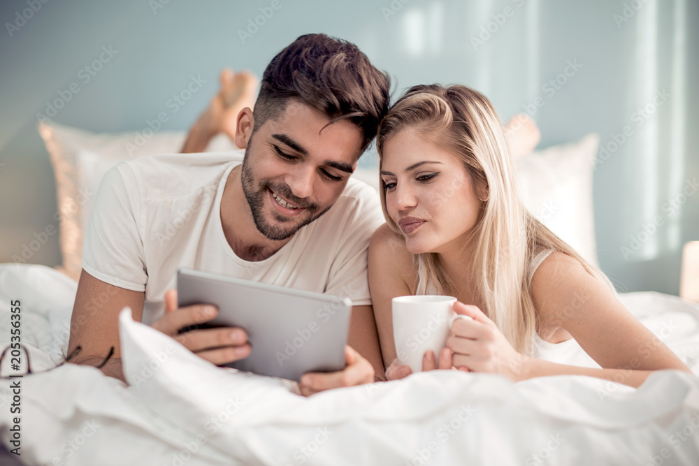Couple using tablet in their bedroom Couple using tablet in their bedroom