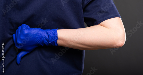 Close-up of female dentist wearing scrubs showing dislike gesture.