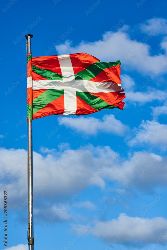 Ikurrina, Basque Country flag waving on a blue sky.