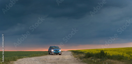 GOMEL, BELARUS - May 15, 2018: blue car parked in the field against a stormy sky. photo